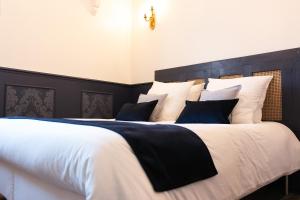 a large bed with black and white sheets and pillows at Domaine La Grange Ungersheim - Chambres d'Hôtes L'Inspiration in Ungersheim