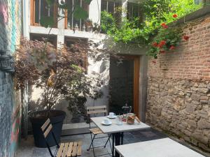 una mesa y sillas en un patio con una pared de ladrillo en Bonjour Pierreuse en Lieja