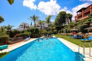 a swimming pool in a resort with people in it at Apartamento en residencial de lujo Los Flamengos in Estepona