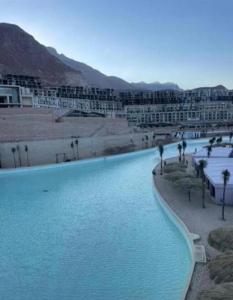 una piscina de agua azul con edificios y palmeras en Il monte galala, en Ain Sokhna