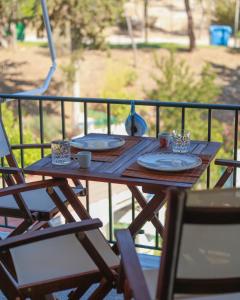a wooden table with plates and cups on a balcony at Vivid Stays Petralona in Athens