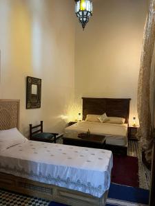 a bedroom with two beds and a chandelier at Riad Ranya in Fez