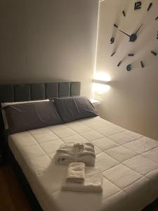 a bed with a towel and a clock on the wall at Cucchiari Suite 8B in Modena