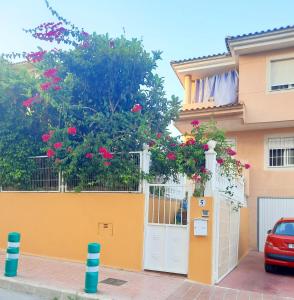 a yellow house with a white gate and pink flowers at Chalet luminoso in Alfaz del Pi