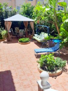 un patio con sombrilla, sillas y plantas en Chalet luminoso en Alfaz del Pi