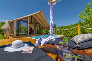 a deck with a hammock and a house with a pool at Floria Glamping Garden in Labin