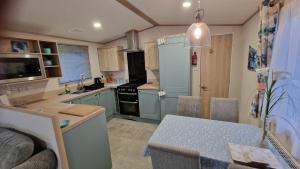 una cocina con armarios azules y una mesa. en Roecliff en St Austell