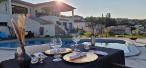 una mesa con copas de vino y servilletas junto a una piscina en Villa Bistinetti Rez de villa tout confort avec piscine, en Penta-di-Casinca