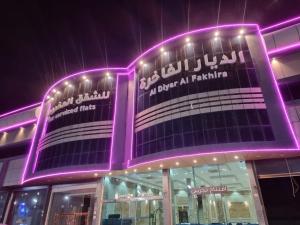 um edifício com luzes roxas em cima em الديار الفاخرة للشقق المخدومة em Al Qunfudhah