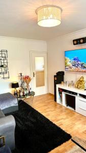 ein Wohnzimmer mit einem Sofa und einem Flachbild-TV in der Unterkunft Premium Wohnung in Bestlage! in München