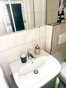 ein Badezimmer mit einem weißen Waschbecken und einem Spiegel in der Unterkunft Premium Wohnung in Bestlage! in München