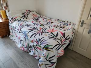 a bed with a floral comforter in a bedroom at Wulfstan House Quiet, Neat, Comfy - 2 min to Central line, Westfield, Notting hill in London