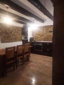 a kitchen with a table and chairs and a stone wall at Casa de Piatra in Socolari +53 photos