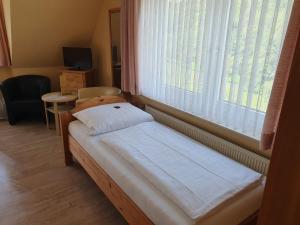 ein kleines Bett in einem Zimmer mit einem großen Fenster in der Unterkunft Brauner Hirsch in Hannoversch Münden