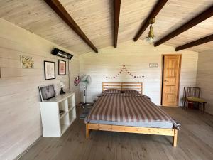 een slaapkamer met een bed in een kamer met houten wanden bij Kaimukas - namelis prie ežero dviems in Rimėnai