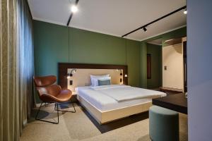 - une chambre avec un lit et une chaise dans l'établissement Hotel Westend, à Nuremberg