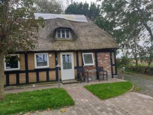 a small house with a thatched roof at Cozy Hideaway - Rustic Charm & Outdoor Adventure 1 in Hornsyld