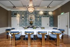 a conference room with a white table and blue chairs at Central Park Voorburg - Relais & Chateaux in Voorburg