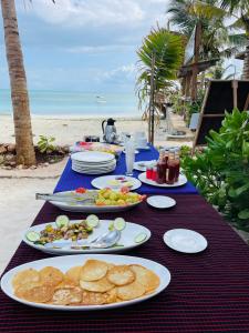 a table with plates of food on the beach at Aquarium Beach House in Nungwi