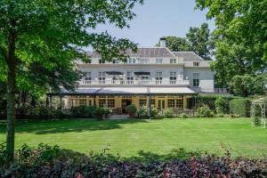 an exterior view of a large white house with a yard at Central Park Voorburg - Relais & Chateaux in Voorburg