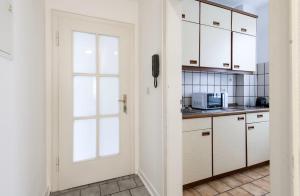 uma cozinha com armários brancos, uma janela e uma porta em City Center Apartment Kleve em Kleve
