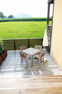 eine Terrasse mit einem Tisch, Stühlen und einem Feld in der Unterkunft Apartmenthotel 's Mitterndorf in Traunkirchen