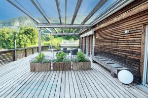 una terraza de madera con dos bancos y plantas. en Apartmenthotel 's Mitterndorf en Traunkirchen