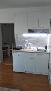 a kitchen with white cabinets and a sink at Apartman LISA in Niš