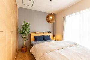 1 dormitorio con 1 cama y una maceta en 佐賀インターナショナルゲストハウスHAGAKURE 2号店, en Saga