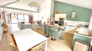 Villa Moderne + Guest House + Piscine chauffée في غوجان-ميستراس: مطبخ وغرفة معيشة مع طاولة وكراسي بيضاء