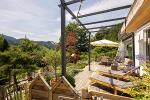 a deck with a table and chairs and an umbrella at Waldlounge - Gartenwohnung in Oberstaufen