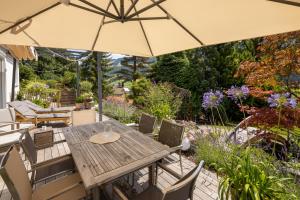 a wooden table and chairs under an umbrella in a garden at Waldlounge - Gartenwohnung in Oberstaufen +7 photos