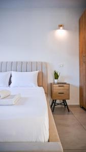a bedroom with a white bed and a wooden nightstand at Nofesh Arbel Suite with Jacuzzi near Sea of Galilee in Migdal