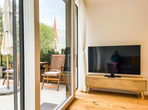 een woonkamer met een flatscreen-tv naast een raam bij Garden Apartment Untermühle in Bressanone