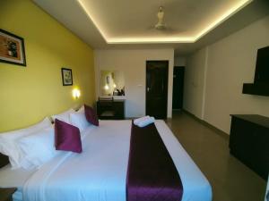 a bedroom with a large white bed with purple pillows at North Centre in Cochin