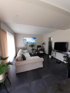uma sala de estar com um sofá branco e uma televisão de ecrã plano em Chambre d'hôte près de Paris em Épinay-sur-Seine