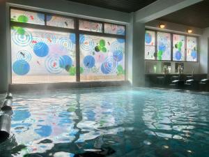 a swimming pool in a room with a wall of windows at Goyokan in Izu