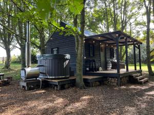 uma pequena cabana preta com um alpendre e uma árvore em Luxury Woodland Lodge em Newport Pagnell