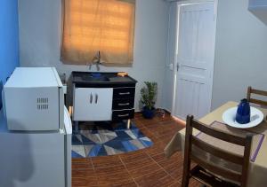 a kitchen with a white refrigerator and a table with at Dith's House (kitnet 1) in Campos do Jordão