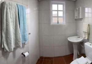 a white bathroom with a sink and a toilet at Dith's House (kitnet 1) in Campos do Jordão