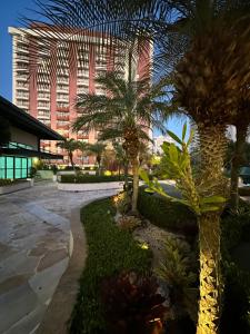 a courtyard with palm trees and a tall building at Flat com Vista Panorâmica -15- na Barra da Tijuca - Estacionamento Gratuito - Frigobar - Ar condicionado - Piscina - Academia - Balsa para Praia Grátis - Varanda - Vista Parcial Mar e Lagoa in Barra da Tijuca