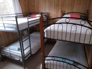 a room with three bunk beds and a window at Surfside two-bedroom holiday upstairs in Batemans Bay