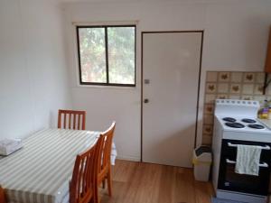 a kitchen with a table and a stove and a window at Surfside two-bedroom holiday upstairs in Batemans Bay