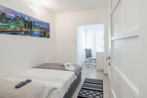 een witte slaapkamer met een bed en een stoel bij Apartment Tree Of Life in Kaštela