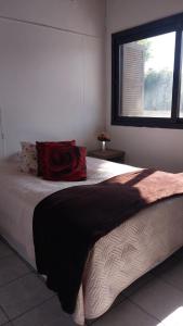 阿雷格里港的住宿－Vila das flores，一间卧室配有一张带红色枕头的床和窗户