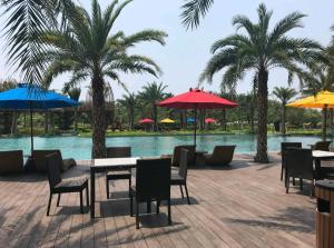 a patio with tables and chairs and umbrellas next to a pool at Studio Apartment at Gold Coast PIK in Jakarta