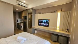 a bedroom with a bed and a flat screen tv at Studio Apartment at Gold Coast PIK in Jakarta