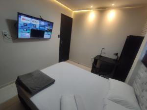 een slaapkamer met een bed en een tv aan de muur bij Praia do Bessa, Caribessa - Quarto Privativo - Conforto, Paz e Sossego, excelente para descansar, trabalhar ou estudar in João Pessoa