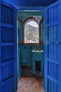 Baño azul con lavabo y ventana en Dar Zambra, en Chefchaouen