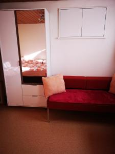 a room with a red couch and a mirror at Ferienzimmer Appenzell in Appenzell